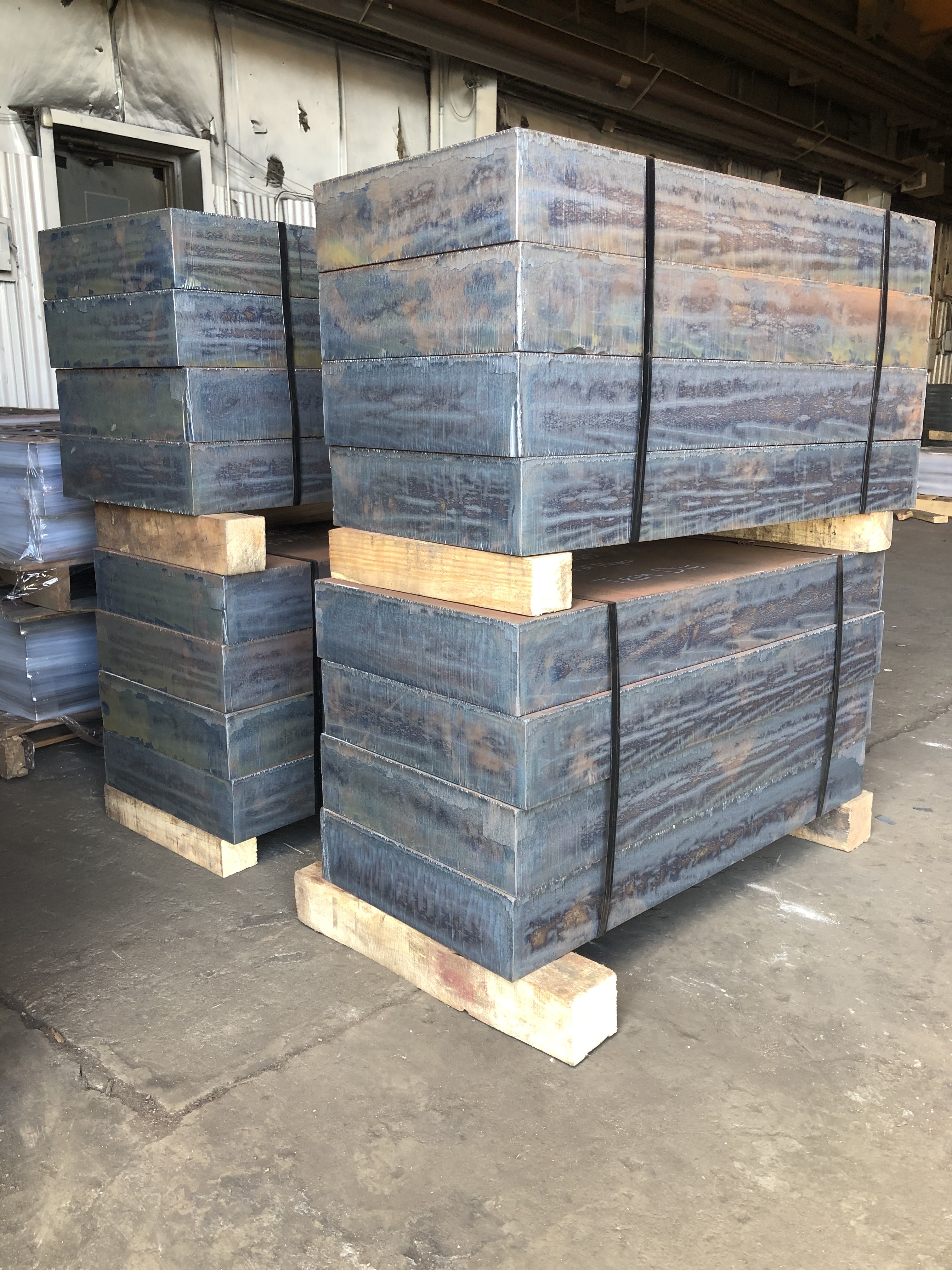 four pallets of large blocks of cut metal in stacks of four